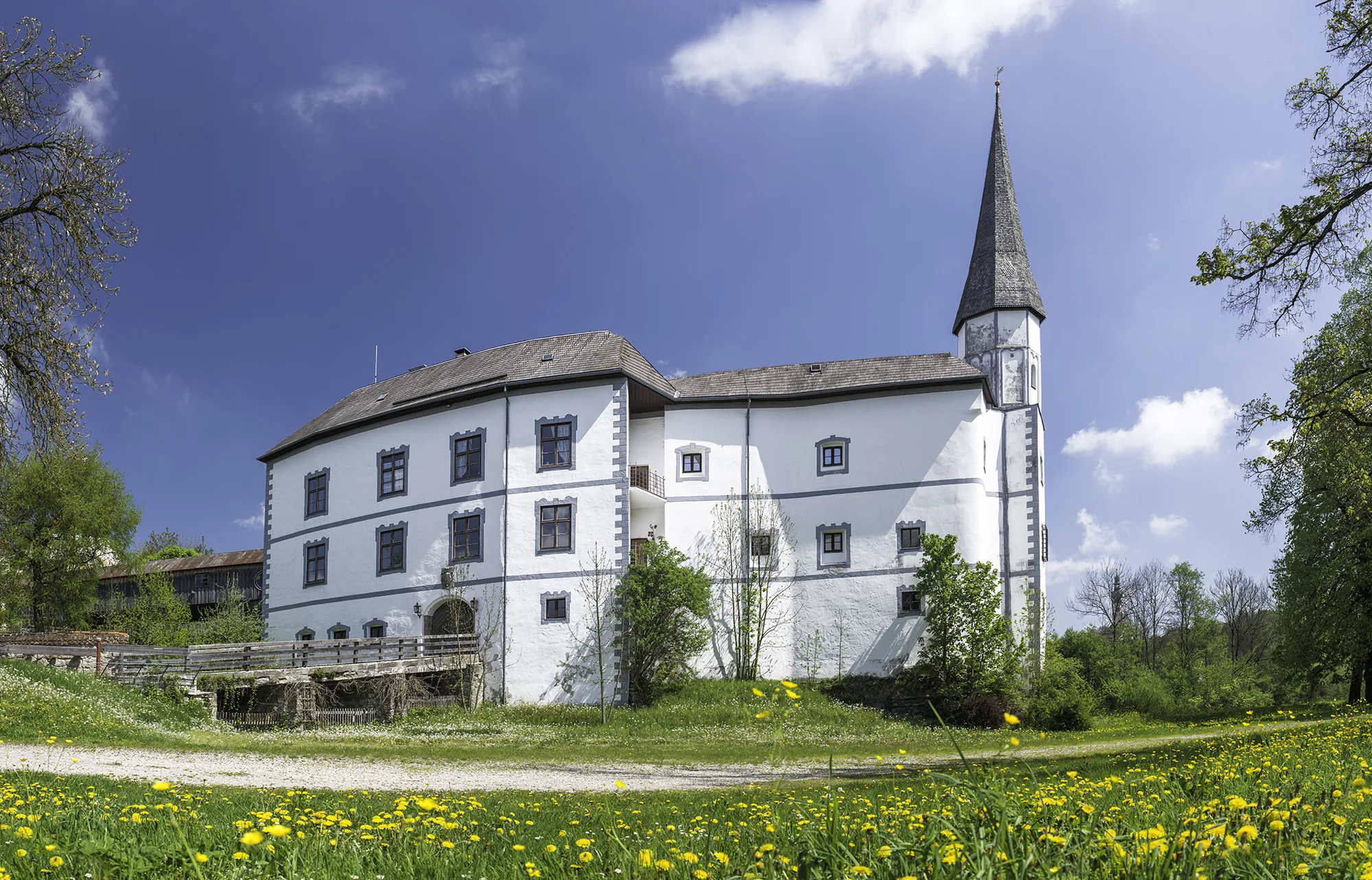Schloss Pertenstein in Traunreut – Außenansicht mit Frühlingswiese